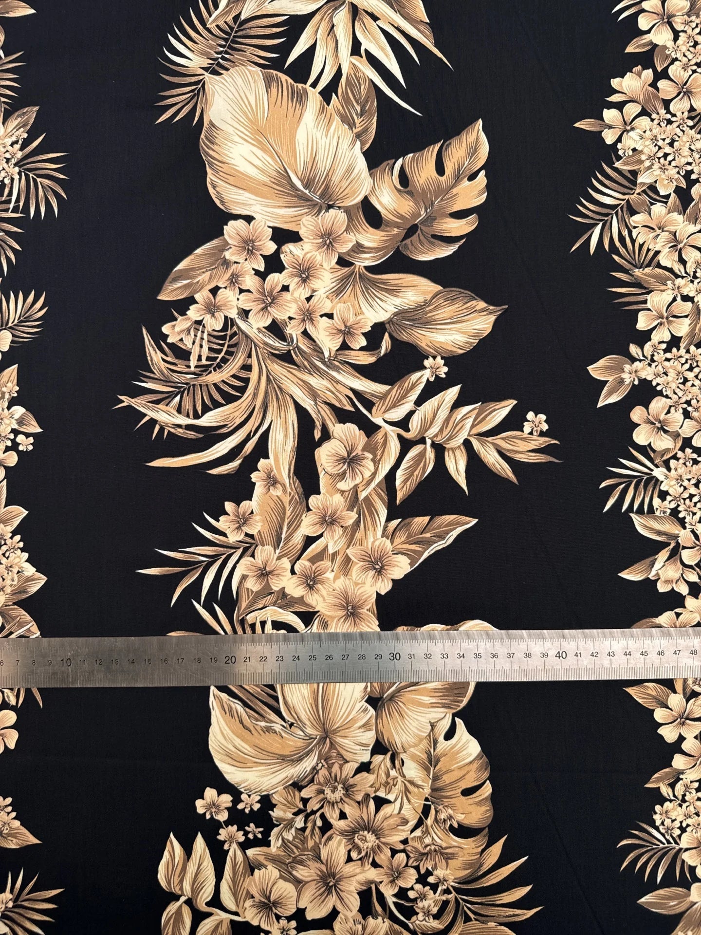 Image d’un tissu en coton italien à motif floral tropical sur fond noir – disponible en ligne chez les tissus de Charlotte