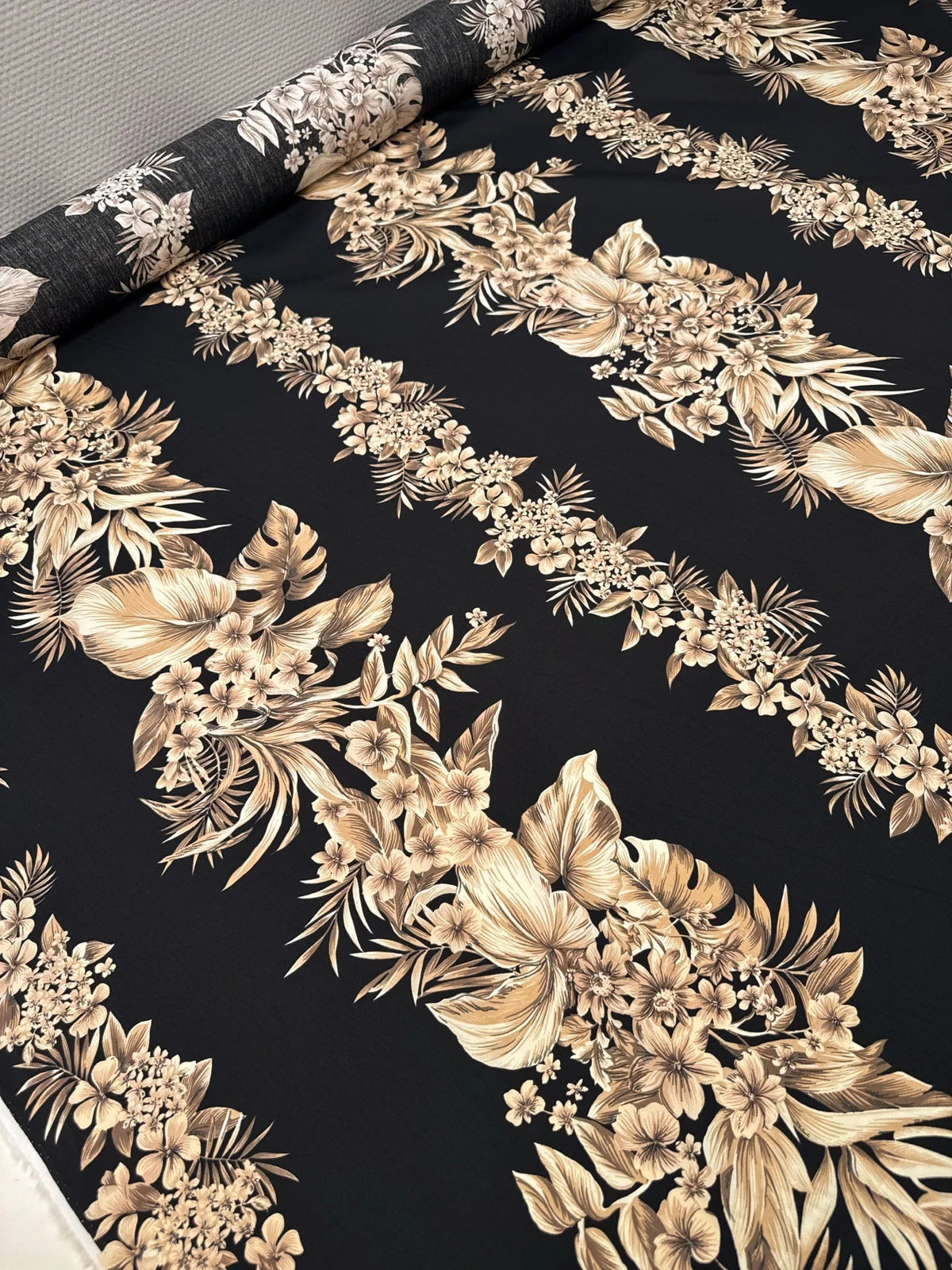 Image d’un tissu en coton italien avec motif floral tropical sur fond noir – disponible en ligne chez Šarlotes audumi