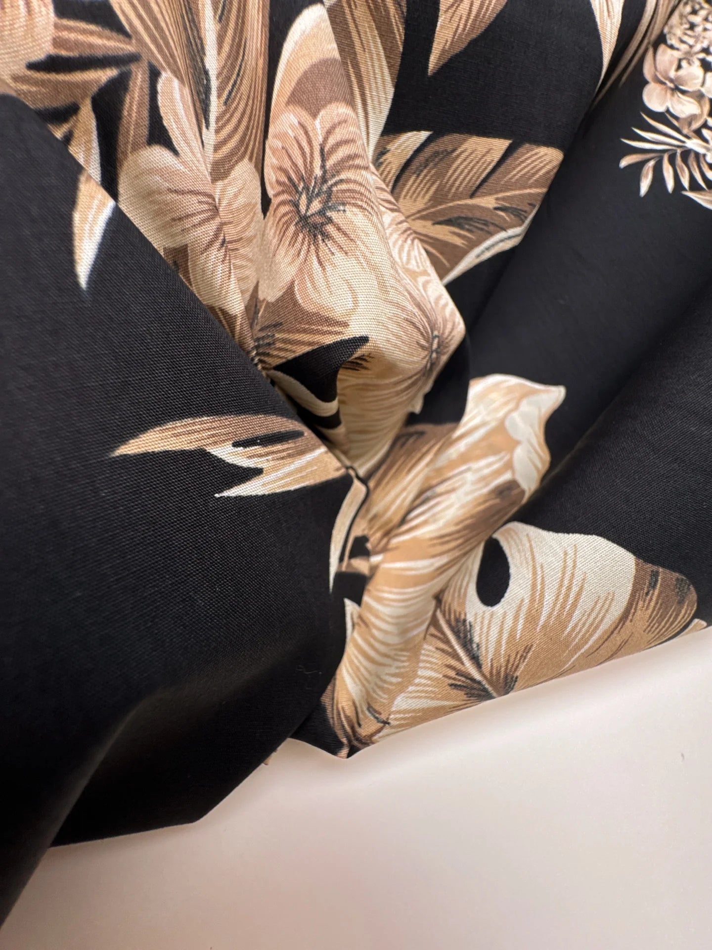 Image d’un tissu en coton italien à motif floral tropical sur fond noir – disponible en ligne chez Šarlotes audumi