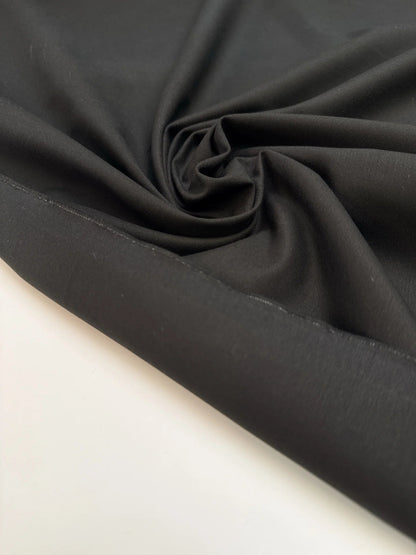 Image du tissu de costume noir en coton avec élasthanne et effet moiré – Italie – disponible en ligne chez Tissus de Charlotte