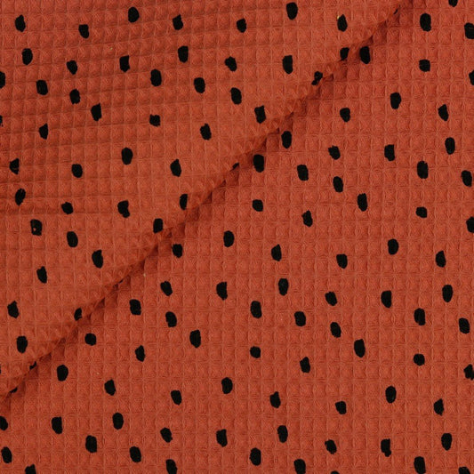 Image of waffle fabric dots on a brick-pink background, 250 g/m² – available at Šarlotes audumi