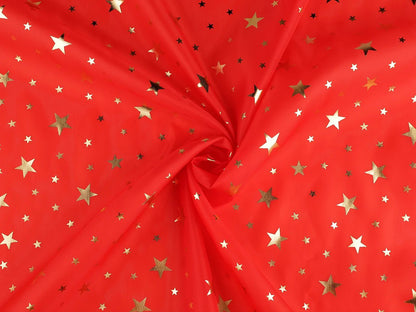 Image d'un tissu décoratif de Noël à étoiles dorées, disponible en ligne chez Šarlotes audumi